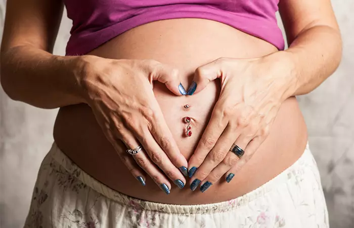 A woman with a belly button piercing during pregnancy.