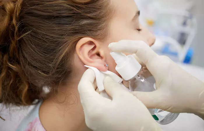 Artist sterilizing their client’s ear lobe piercing