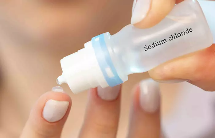 A woman using a saline solution to clean her curated ear piercings