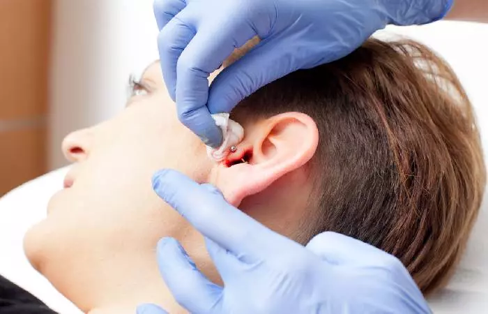 An experienced professional piercing the tragus in a hygienic manner