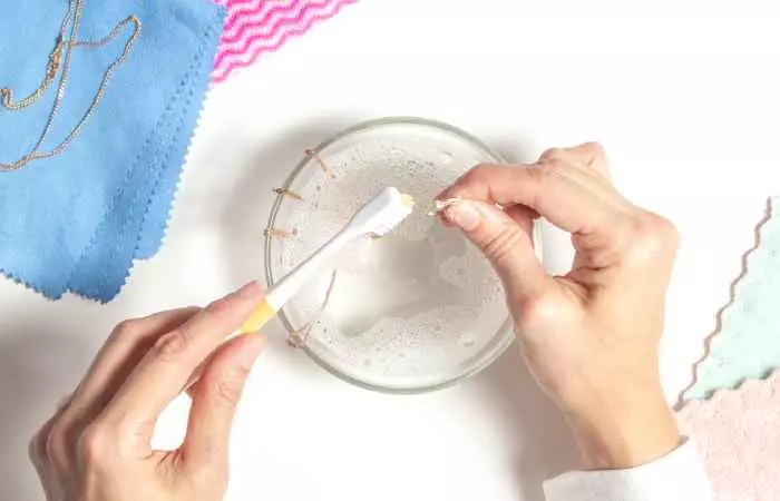 Cleaning piercing jewelry with a brush and antibacterial soap and warm water