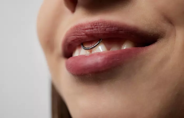 Close-up image of a woman with a smiley piercing