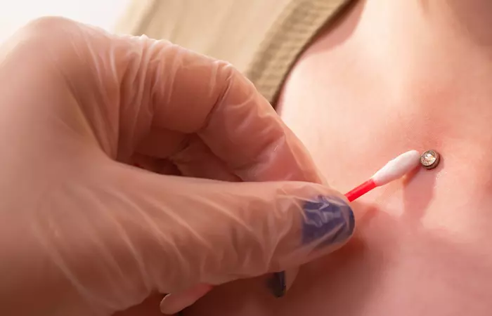 Cleaning a dermal piercing with a cotton bud