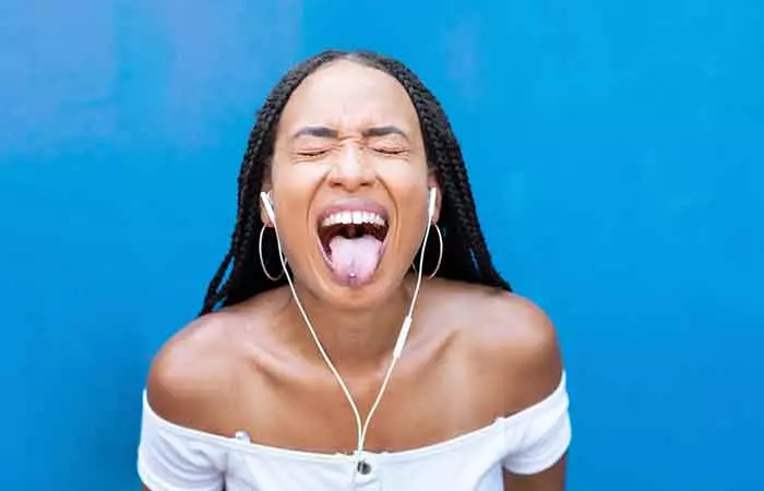 A woman gestures in joy while listening to music, showcasing her tongue piercing