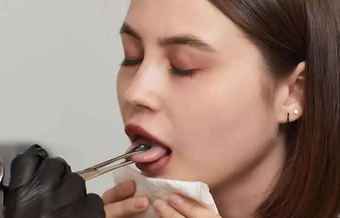 A woman getting her tongue pierced by an expert