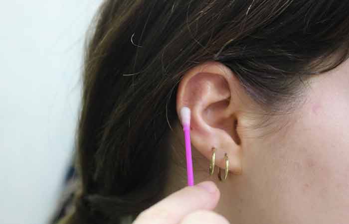 A woman cleaning her pierced area to avoid infection