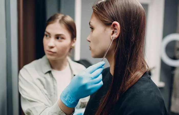 A professional piercer points to a client’s ear to finalize placement