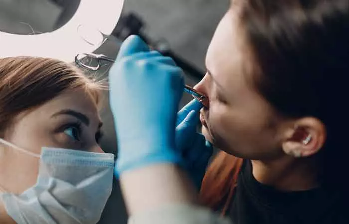 A woman getting her nose pierced