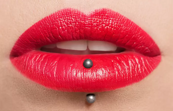 Close up of red lips with a vertical labret piercing