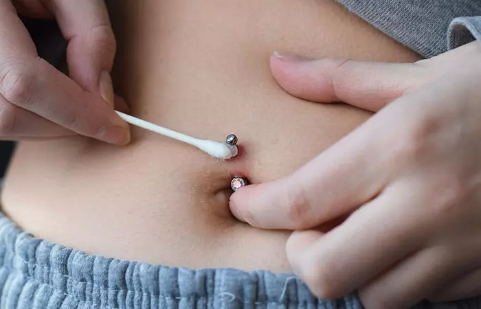 A woman cleaning her belly button piercing