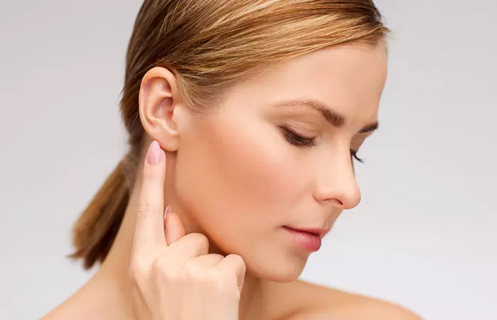 A woman points at her ear as she plans for the ideal curated ear piercings for her