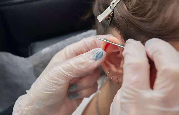 A woman getting an industrial piercing