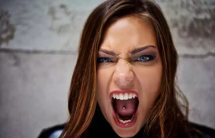 A close-up of a woman with a tongue piercing screaming in anger