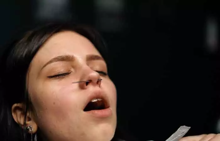 A woman with a nose piercing experiencing pain