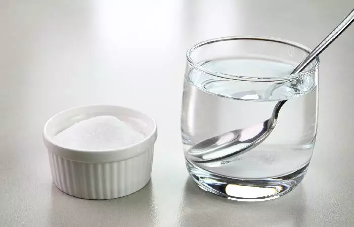 Salt water in a glass cup and salt in a bowl to be used to clean hip piercings