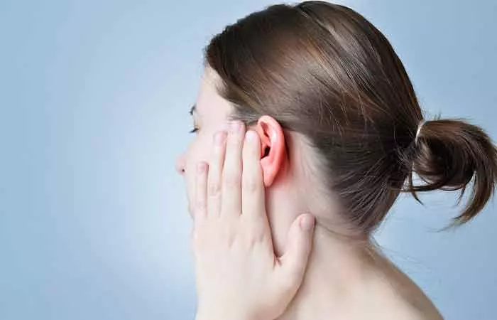A woman touching her inflamed ear after getting a piercing