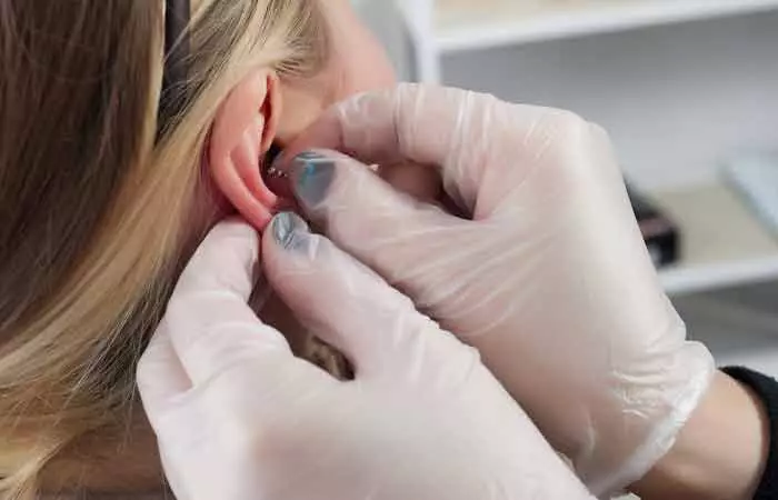 A woman getting her ear pierced by a piercer