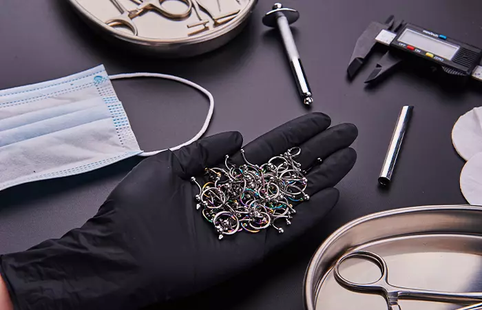 A piercer showing sterilized equipment and jewelry options for vertical labret piercing