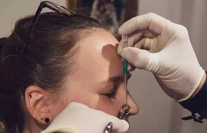 A woman getting her nose pierced with a needle