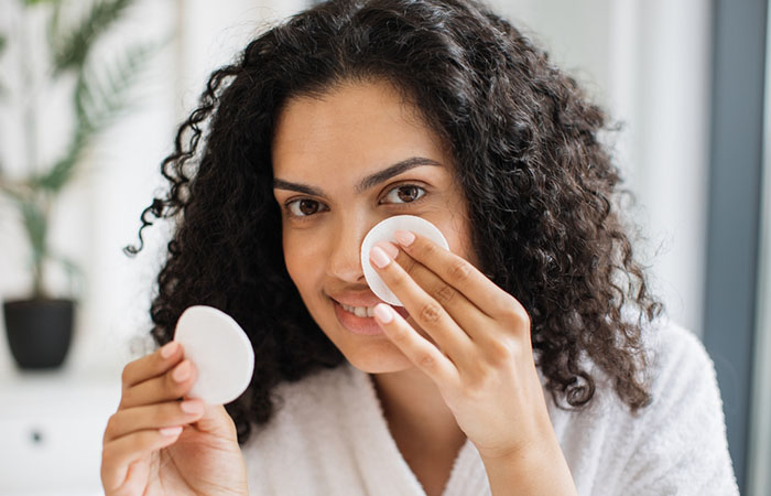 Woman cleans her piercing with a cotton pad