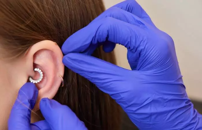 Woman getting a daith piercing on her left ear