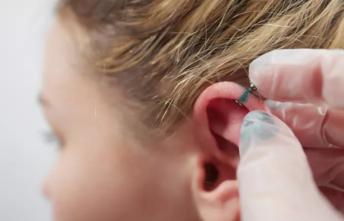 Woman getting a double helix piercing