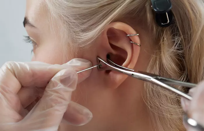 Woman getting a tragus piercing with a professional piercing artist