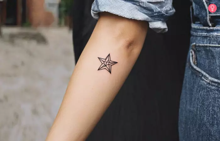 A small star tattoo on a woman’s forearm