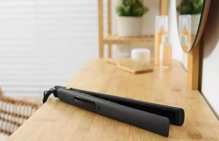 A black flat iron on a wooden table