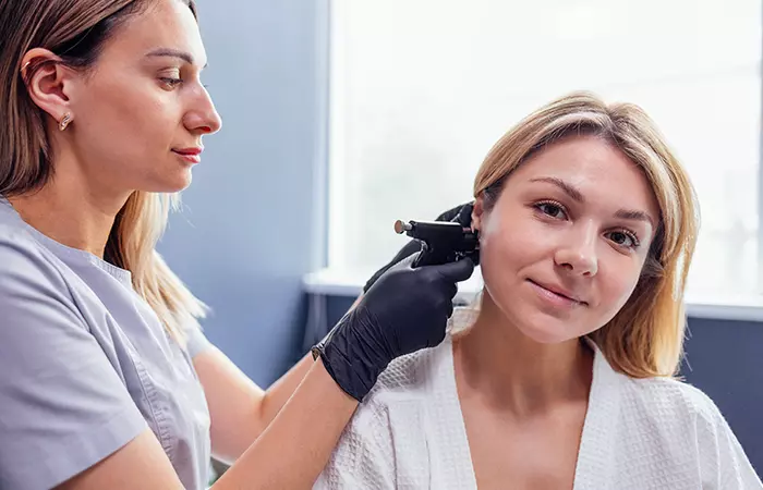 A piercer re-piercing a woman’s earlobe