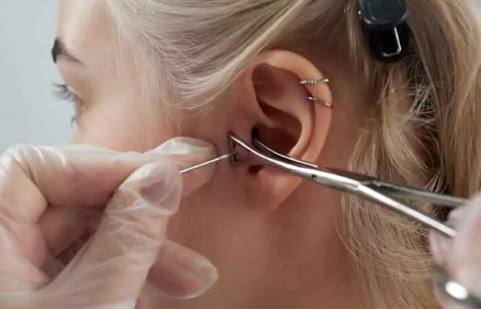 A professional piercer piercing their client’s ear