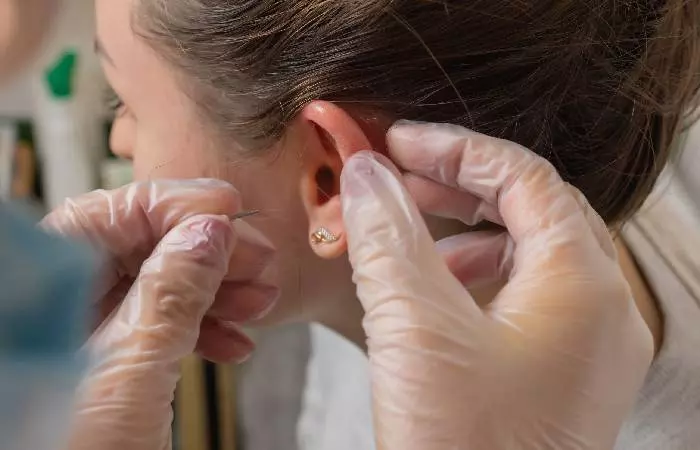 A professional re-piercing a partially closed piercing