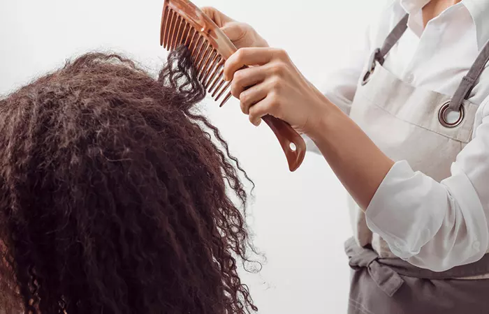 A salon professional detangling hair using a wide-toothed comb