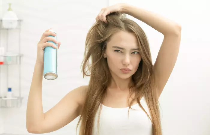 A woman applying hairspray