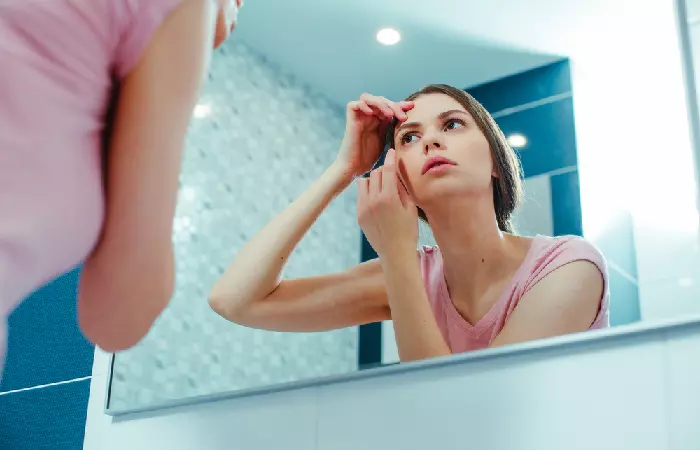 A woman checking her eyebrows in the mirror