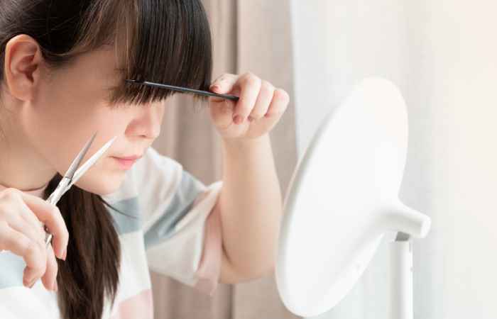 A woman looking into the mirror and cutting hair