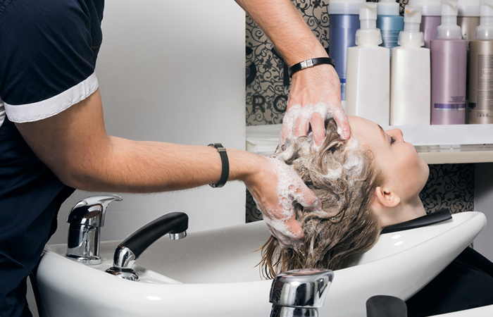 A woman preparing her hair for teasing at a salon