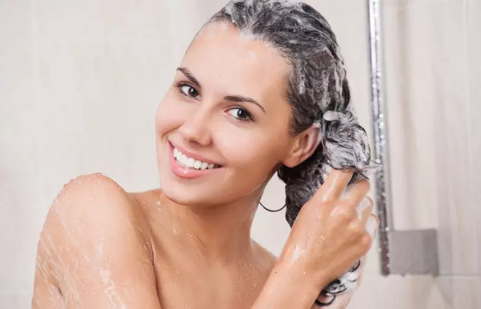 A woman shampooing her hair with volumizing shampoo