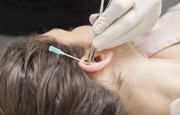 A woman undergoing an ear re-piercing process