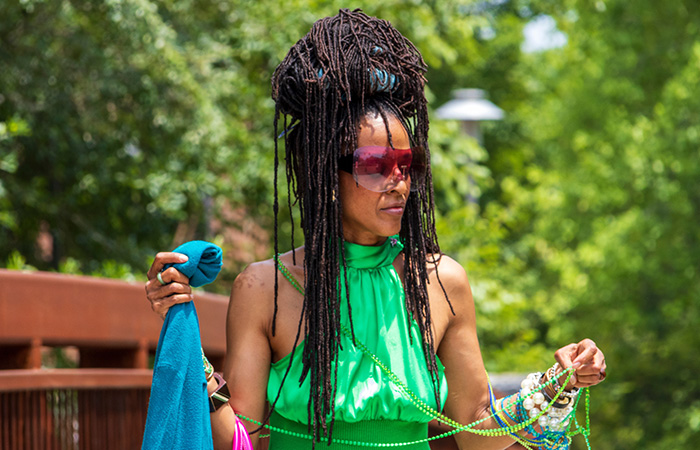 A woman with long Sisterlocks styled into a messy top-bun hairstyle.