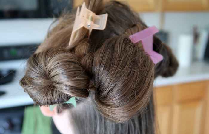 A woman’s hair divided into separate sections with clips