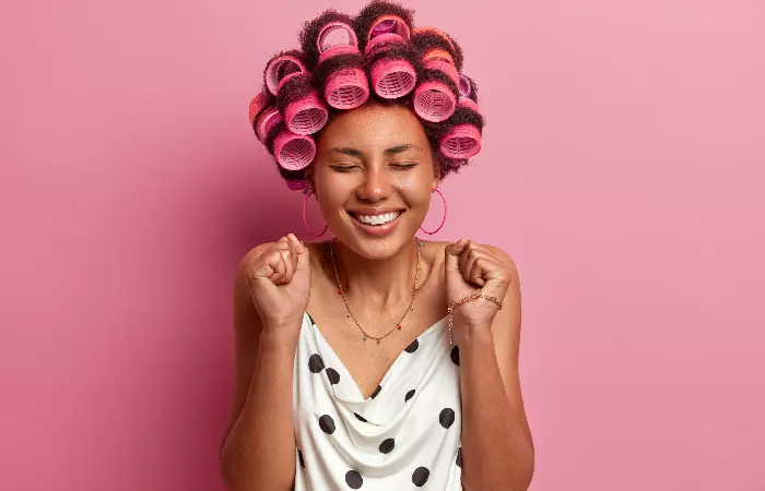 A young woman using hair rollers to create fluffy hair