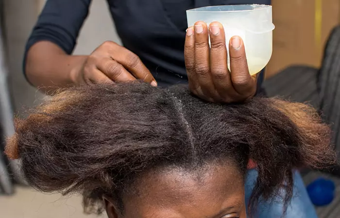 A stylist applying curl cream to dry and parted hair