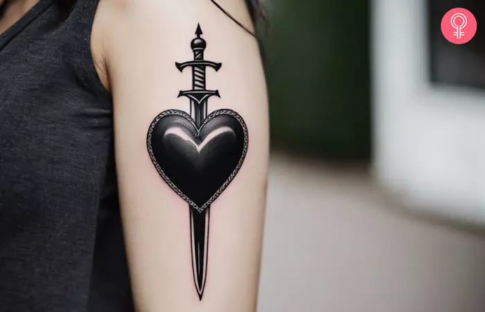 Woman with a black heart and sword tattoo on her arm