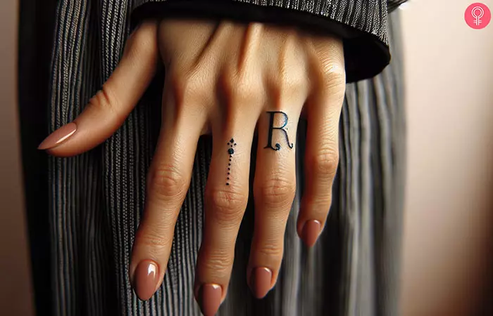 R tattoo with a dot on the ring finger