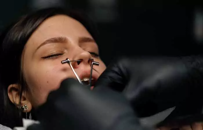 Woman getting a septum piercing done