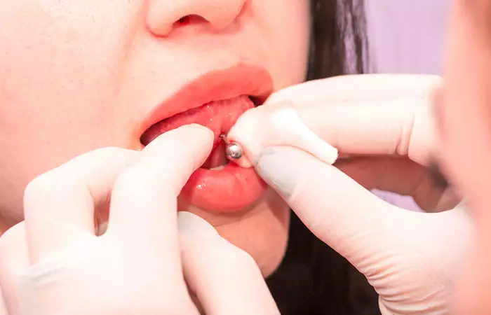 A piercer cleaning her client’s tongue-piercing wound