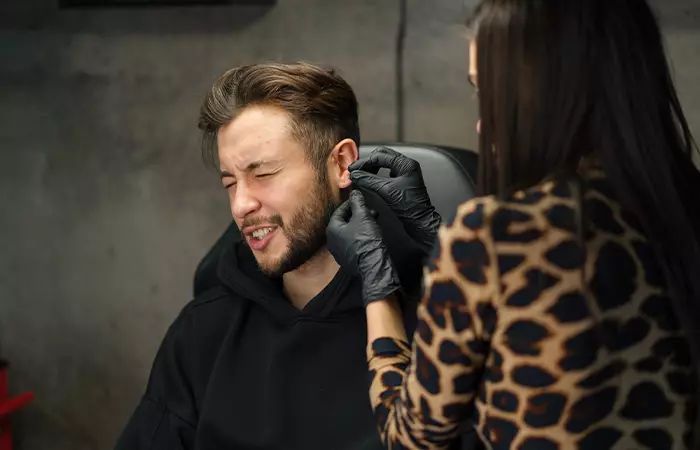 A man getting his ear pierced by a piercing artist