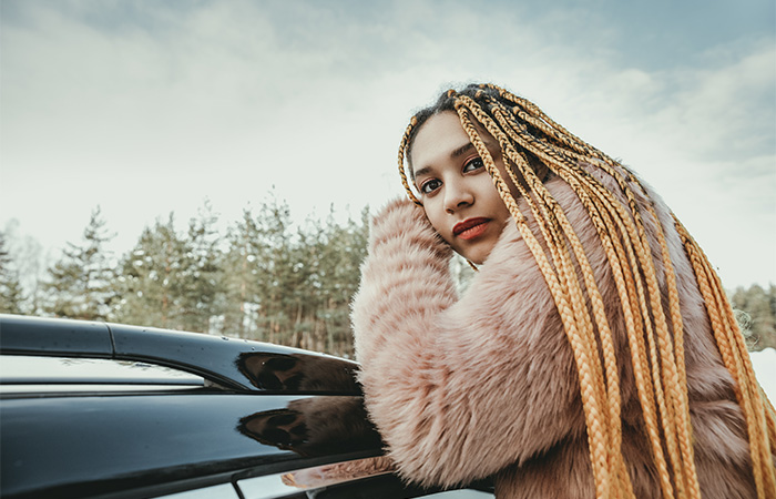 Young woman with dark roots and blonde box braids.