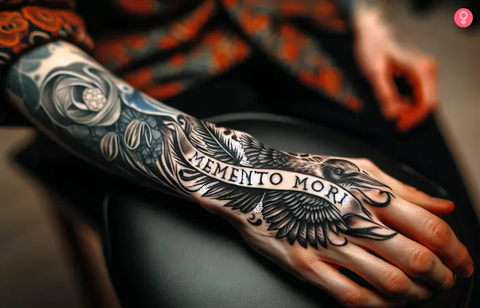 A person with a Memento Mori script tattoo on their hand